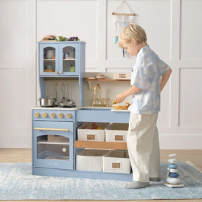 Child playing with a blue wooden play kitchen set 